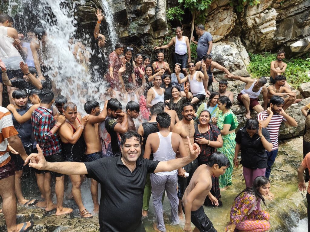 लायंस क्लब सार्थक के वन-विहार कार्यक्रम के दौरान झरने के पास हँसी-ठिठोली करते हुए सदस्यगण; झरना, पकौड़ी, अंत्याक्षरी, और बस डांस की मस्ती से भरी पिकनिक।