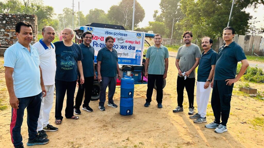 Lions Club Sarthak members distributing buttermilk to locals near a water tank at Church Ground, concluding their 3-month-long free RO water service project amidst cloudy weather.